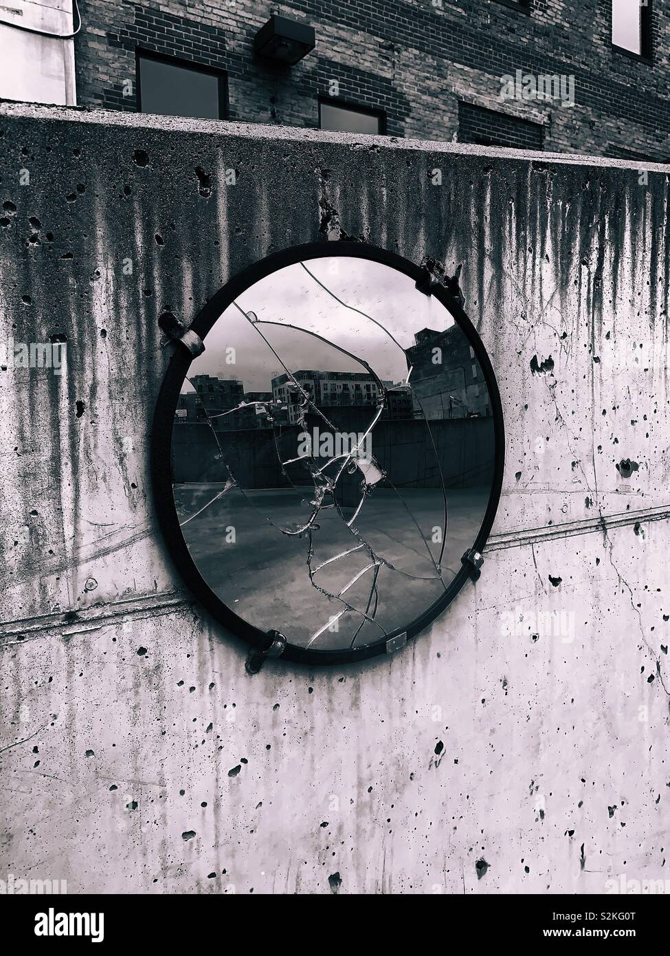 Broken traffic mirror on a concrete retaining wall. Stock Photo