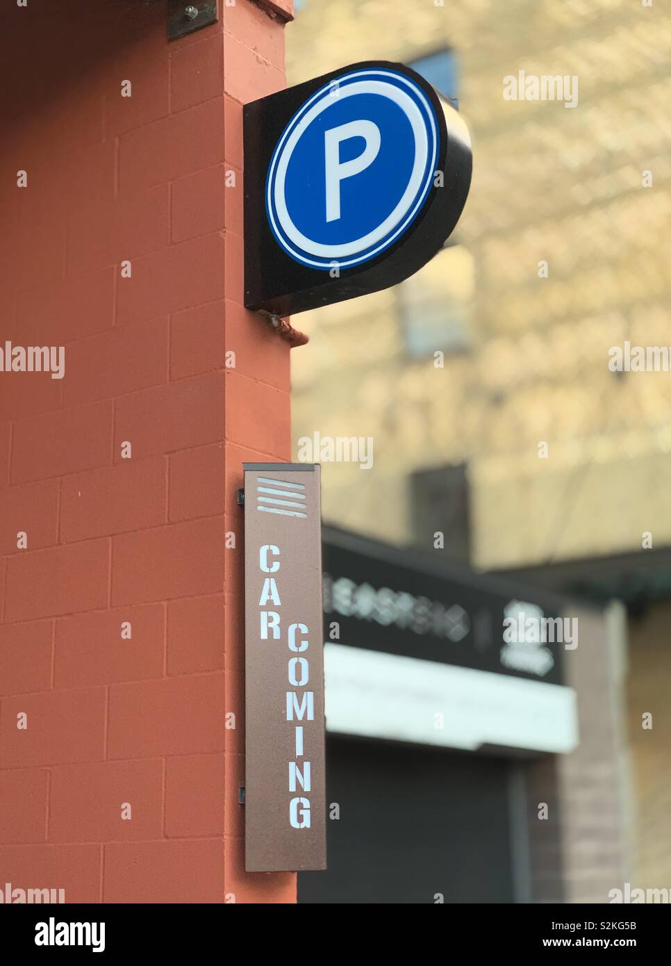 Public parking with “car coming” warning sign. Stock Photo