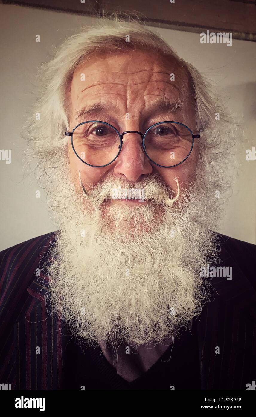 Smiling senior man with white bushy beard and steel rimmed spectacles. Stock Photo