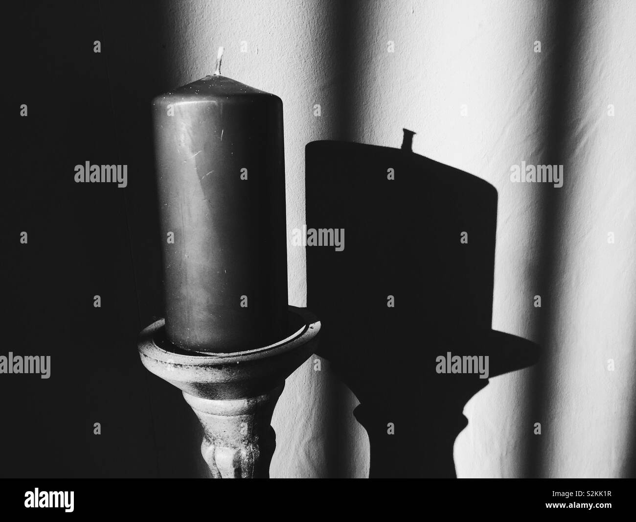 Tall church Candle on holder with shadow. Light play. BW - Smartphone Captured Stock Image