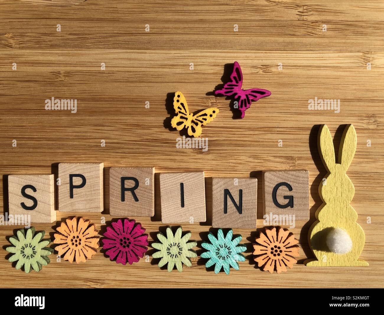 Spring, in wooden letters on wood background with flowers, butterflies and a rabbit Stock Photo