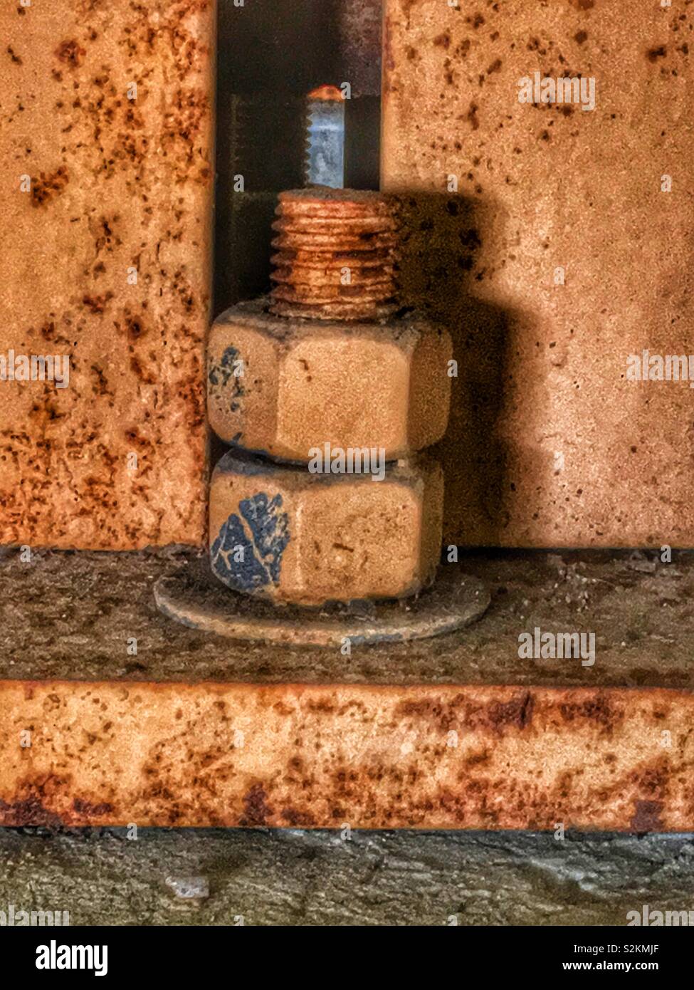 Strong worn and rusty steel bolt connection with nuts, a threaded bolt, a washer, and plate. - Smartphone Captured Stock Image
