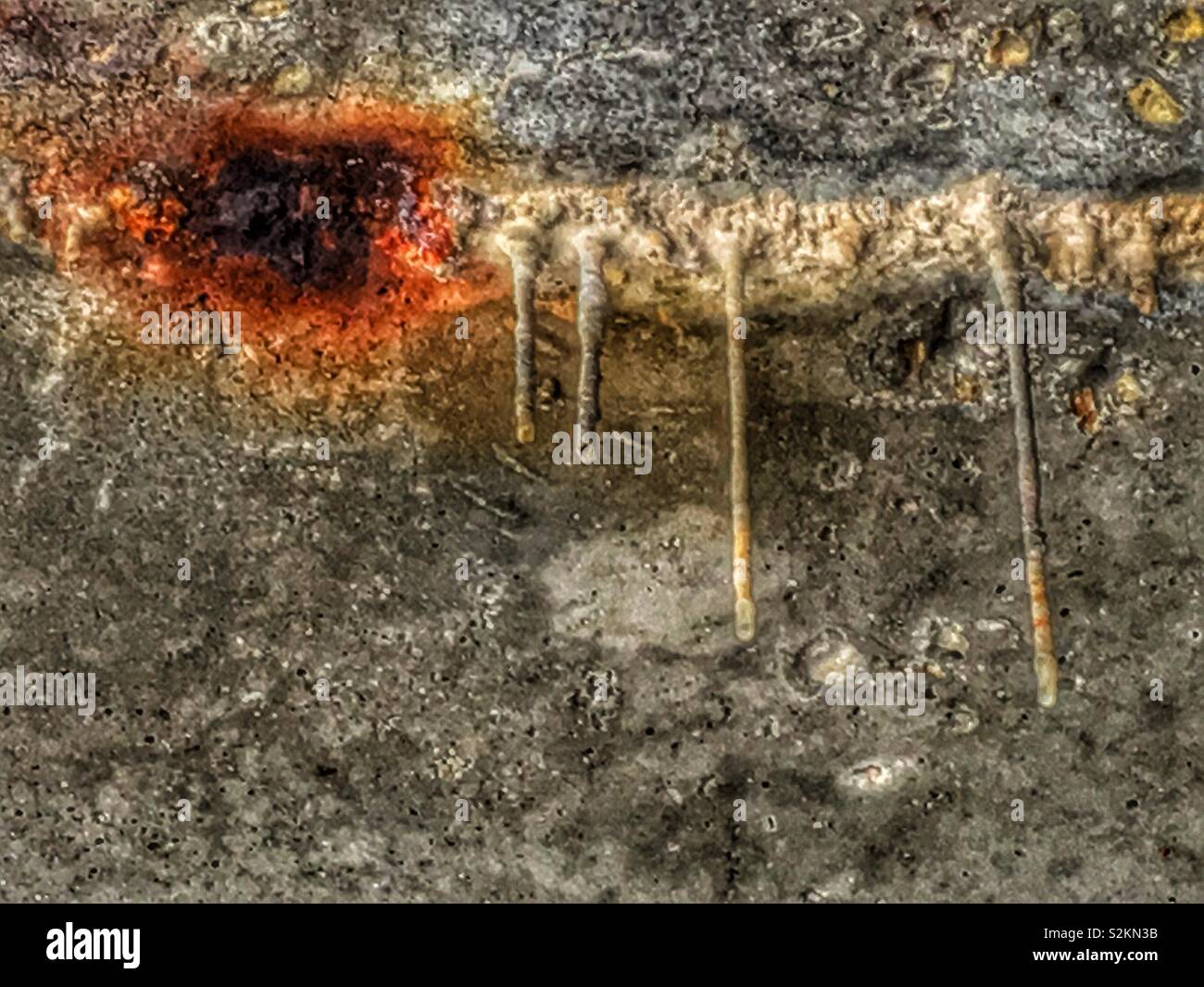 Authentic urban mineral stalactite with drippings hanging from the cracked concrete ceiling. - Smartphone Captured Stock Image