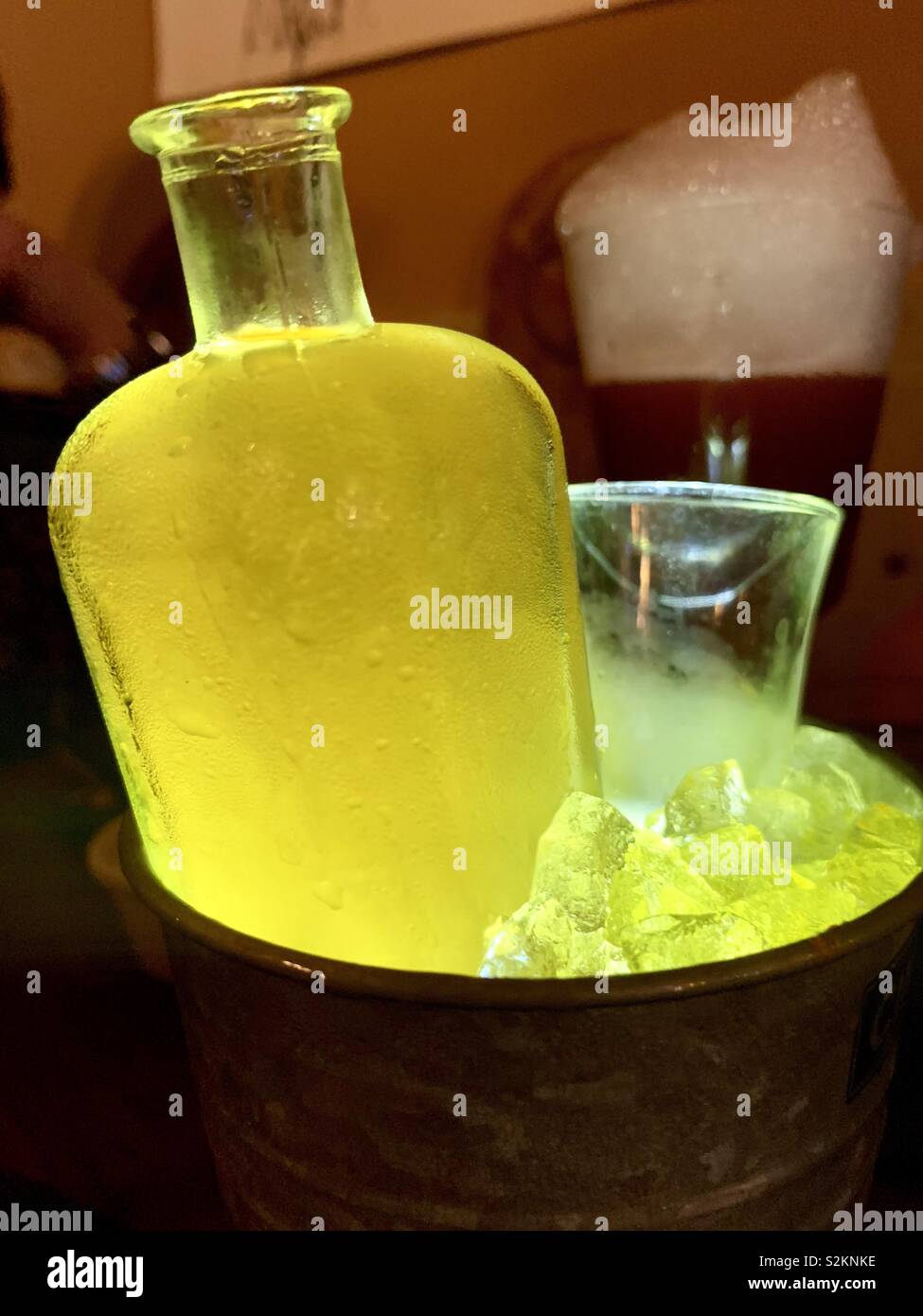 Colorful bottle in a ice bucket close-up with cocktail in the background Stock Photo