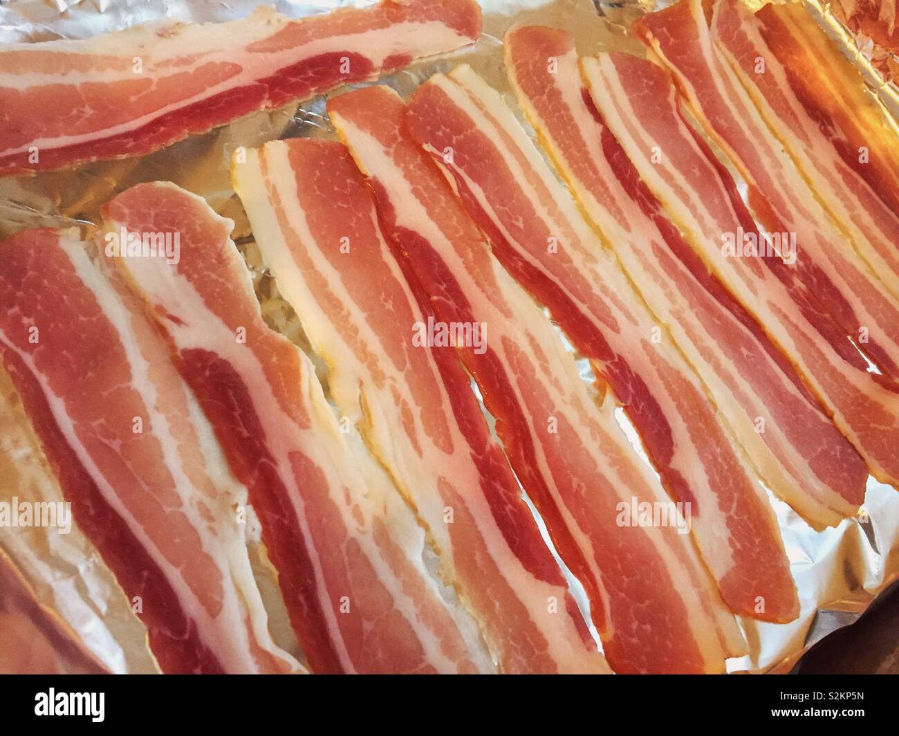 Tray of bacon.  Pancetta style streaky bacon ready to be grilled and cooked for breakfast.  Rasher or rashers linked to cancer Stock Photo