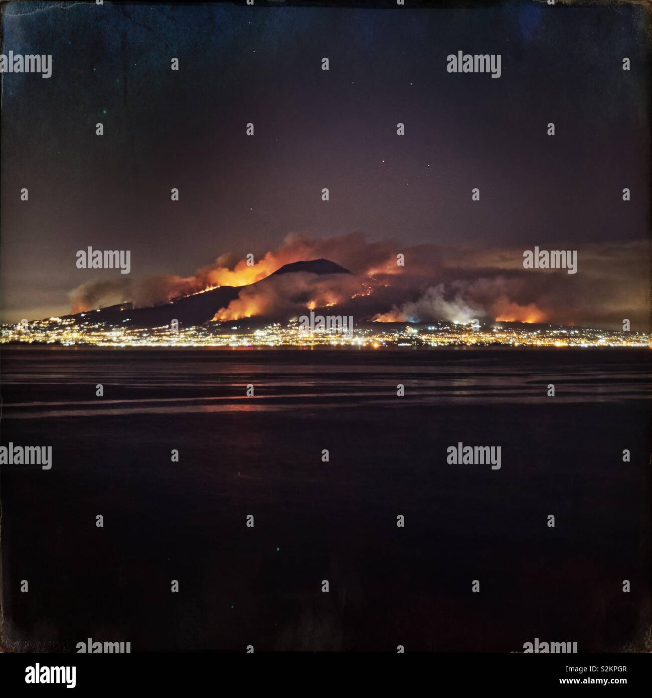 Night image of wild fires burning on Mount Vesuvius volcano, viewed across the Gulf of Naples, Italy Stock Photo