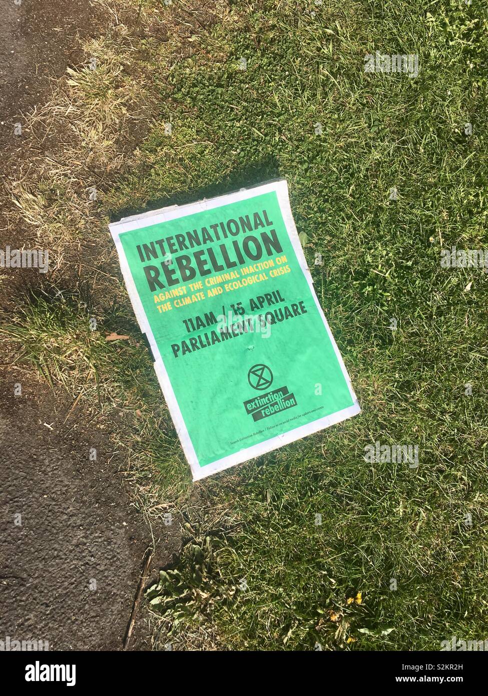 International Rebellion poster to take action against climate change on 15th April, 2019 discarded as litter on ground Stock Photo