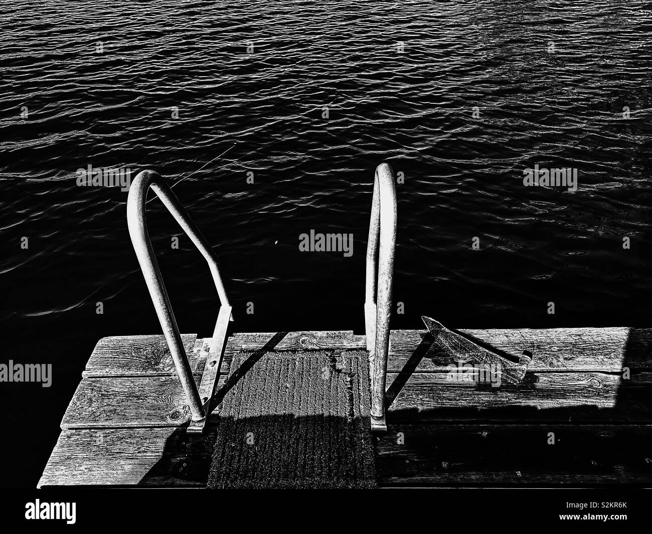 Wooden jetty with piece of ice and ladder into lake, Sweden Stock Photo