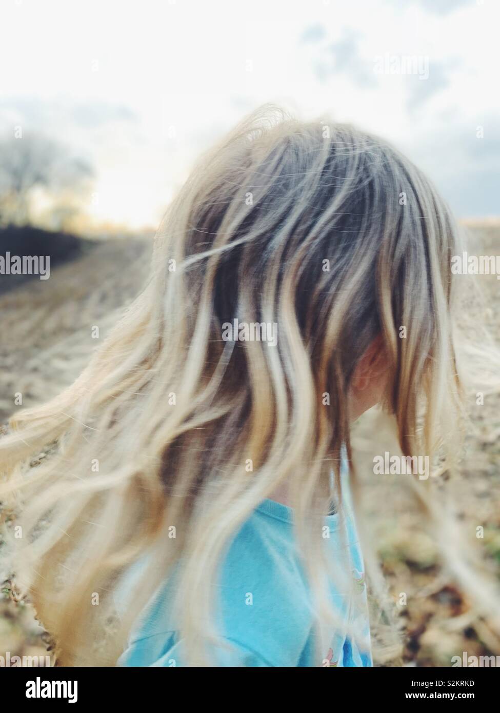 Girl with blonde hair in a field facing away from camera Stock Photo ...