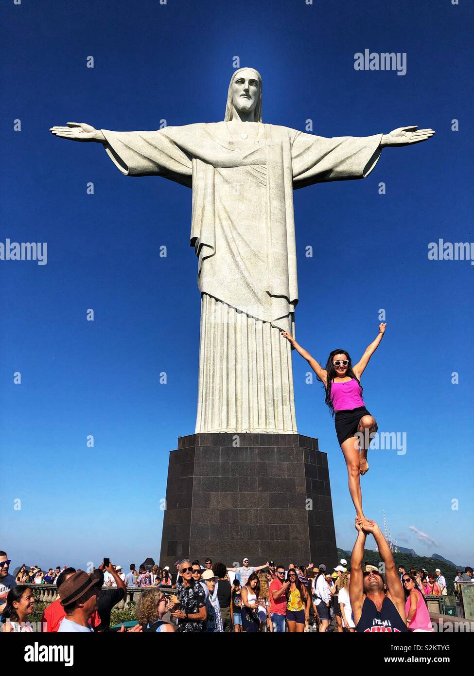 Taking posing to new heights in front of the iconic Christ the Redeemer statue in Rio de Janeiro, Brazil. Stock Photo