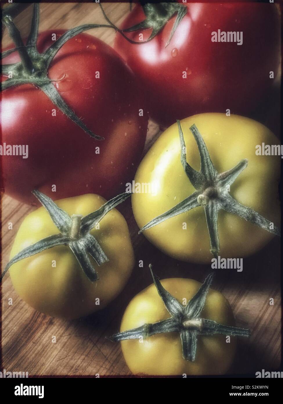 Fresh red and green tomatoes on a wooden cutting board - Smartphone Captured Stock Image