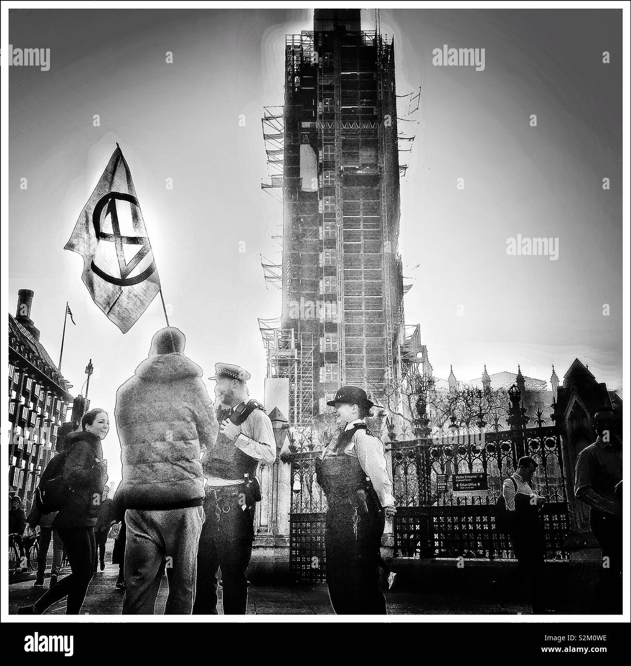 Flag waving Extinction Rebellion eco warrior chats with Police officers below Big Ben in Westminster. - Smartphone Captured Stock Image