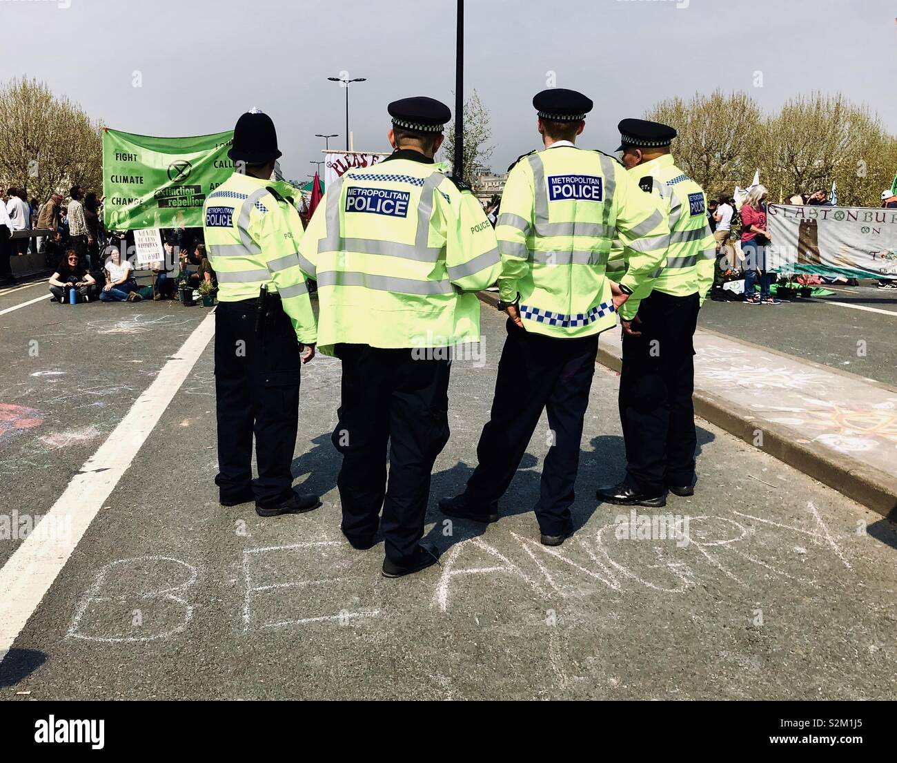 Police gathered in front of the extinction rebellion protest on Waterloo bridge, ‘be angry’ is written in front of them on the road April 2019 Stock Photo