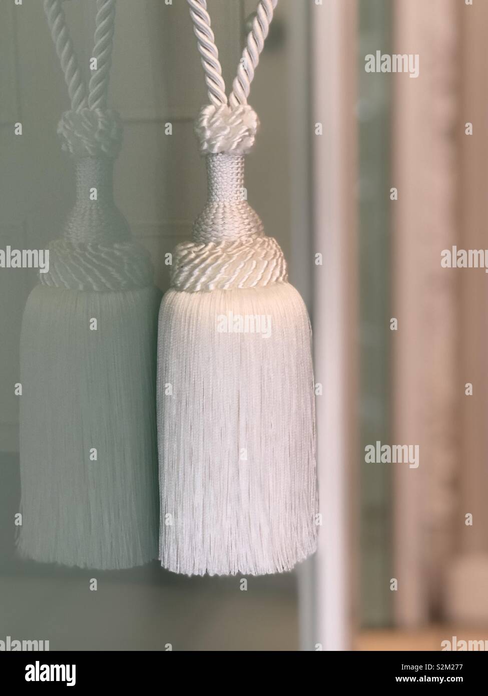 Stylish white cord tassel reflected in glass door - Smartphone Captured Stock Image