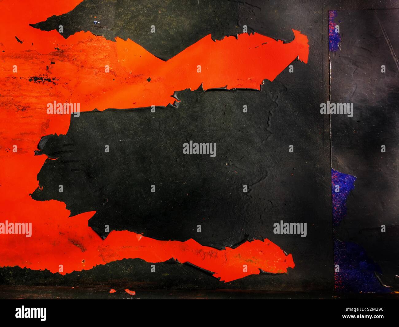 Peeling black paint on red background giving abstract jaw like pattern. - Smartphone Captured Stock Image