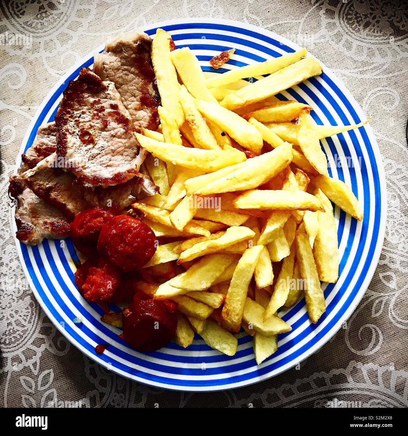Fried potatoes, sausage ( chorizo ) and Iberian meat steaks in Prado del Rey, Sierra de Cadiz, Andalucia, Spain - Smartphone Captured Stock Image