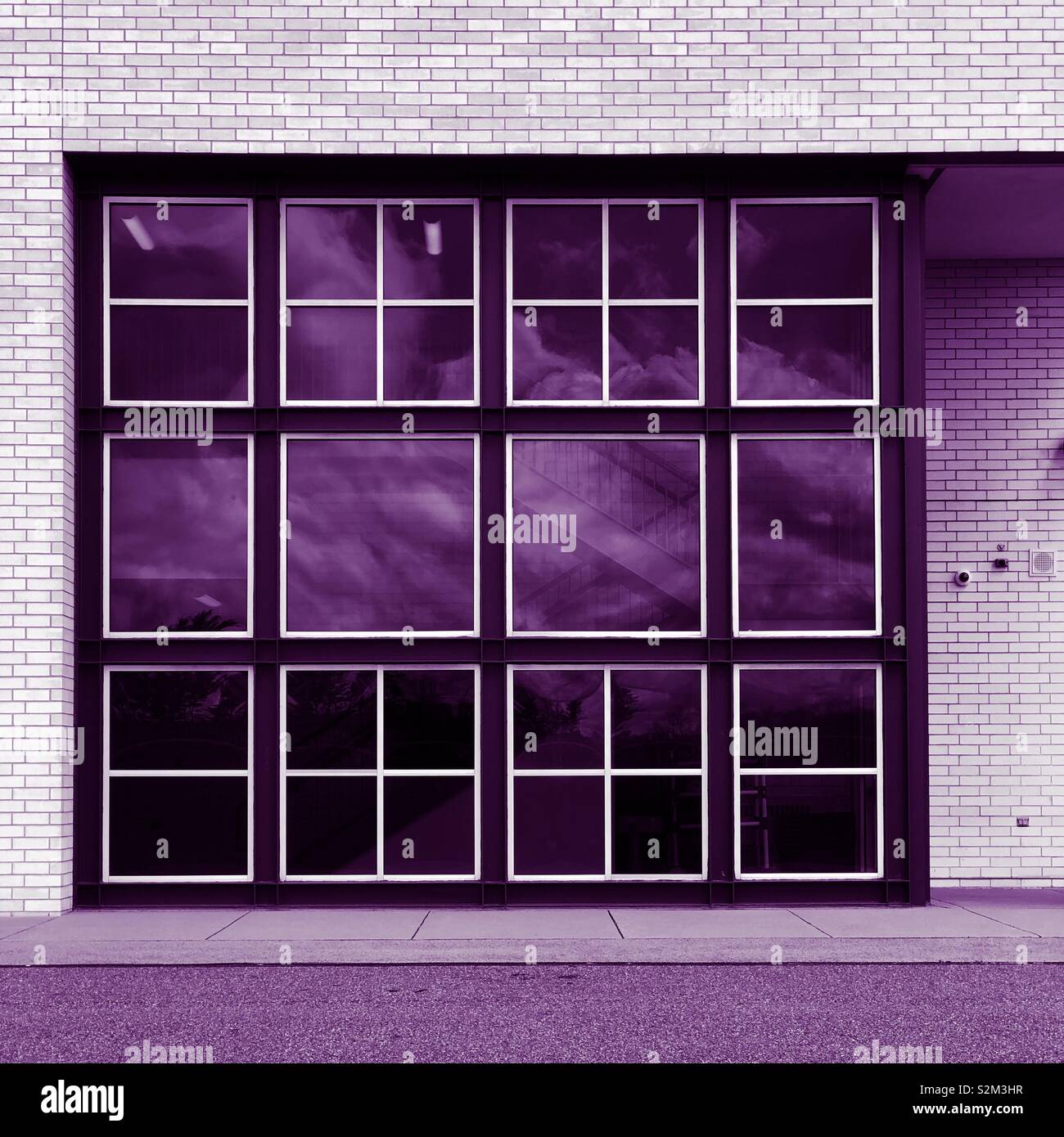 A window with many panes reflecting a cloudy sky with a purple tone - Smartphone Captured Stock Image