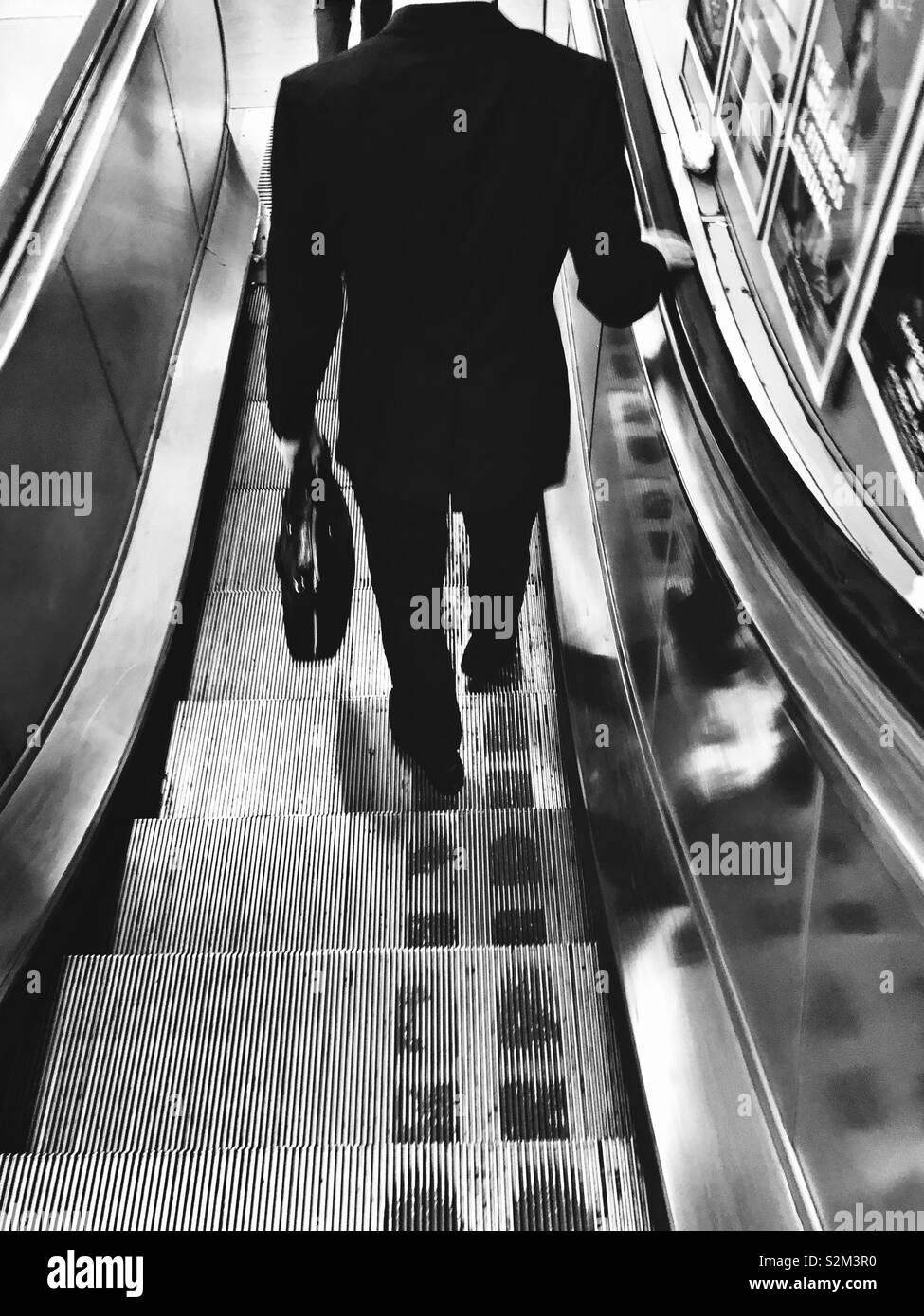 Man in business outfit going down the escalator - Smartphone Captured Stock Image