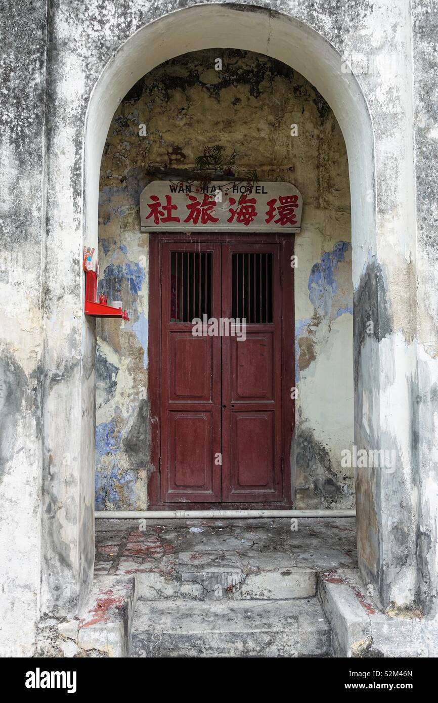 Vintage single hotel door surrounded with some chinese letters. White and red. Vintage, old and weathered. Oldtown Penang, Malaysia Stock Photo