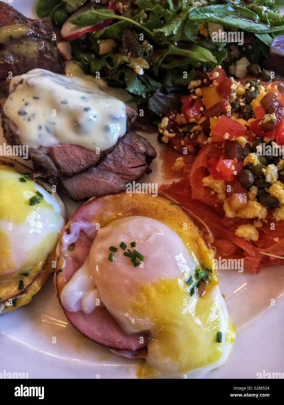 Plate full of delicious brunch buffet food eggs Benedict, baked lamb