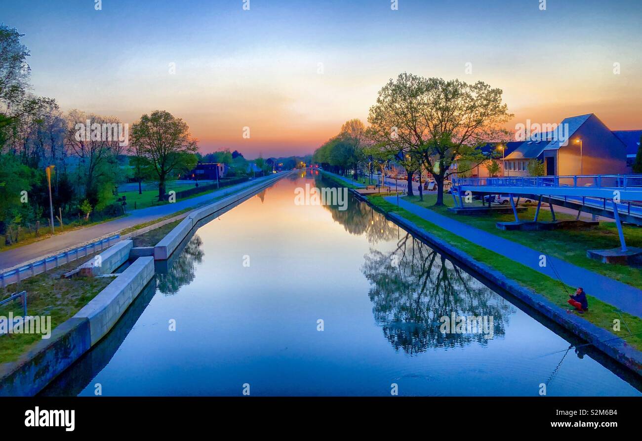 A golden glowing horizon in the sky over a river or canal sunset or sunrise at Dusk or dawn - Smartphone Captured Stock Image