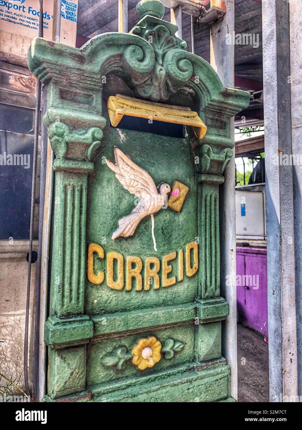 A green mailbox on a house fence. - Smartphone Captured Stock Image