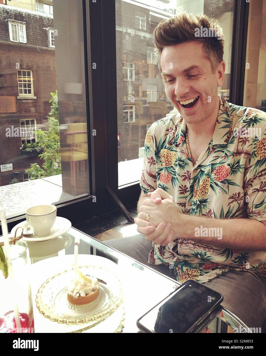 Man laughing at birthday cake - Smartphone Captured Stock Image