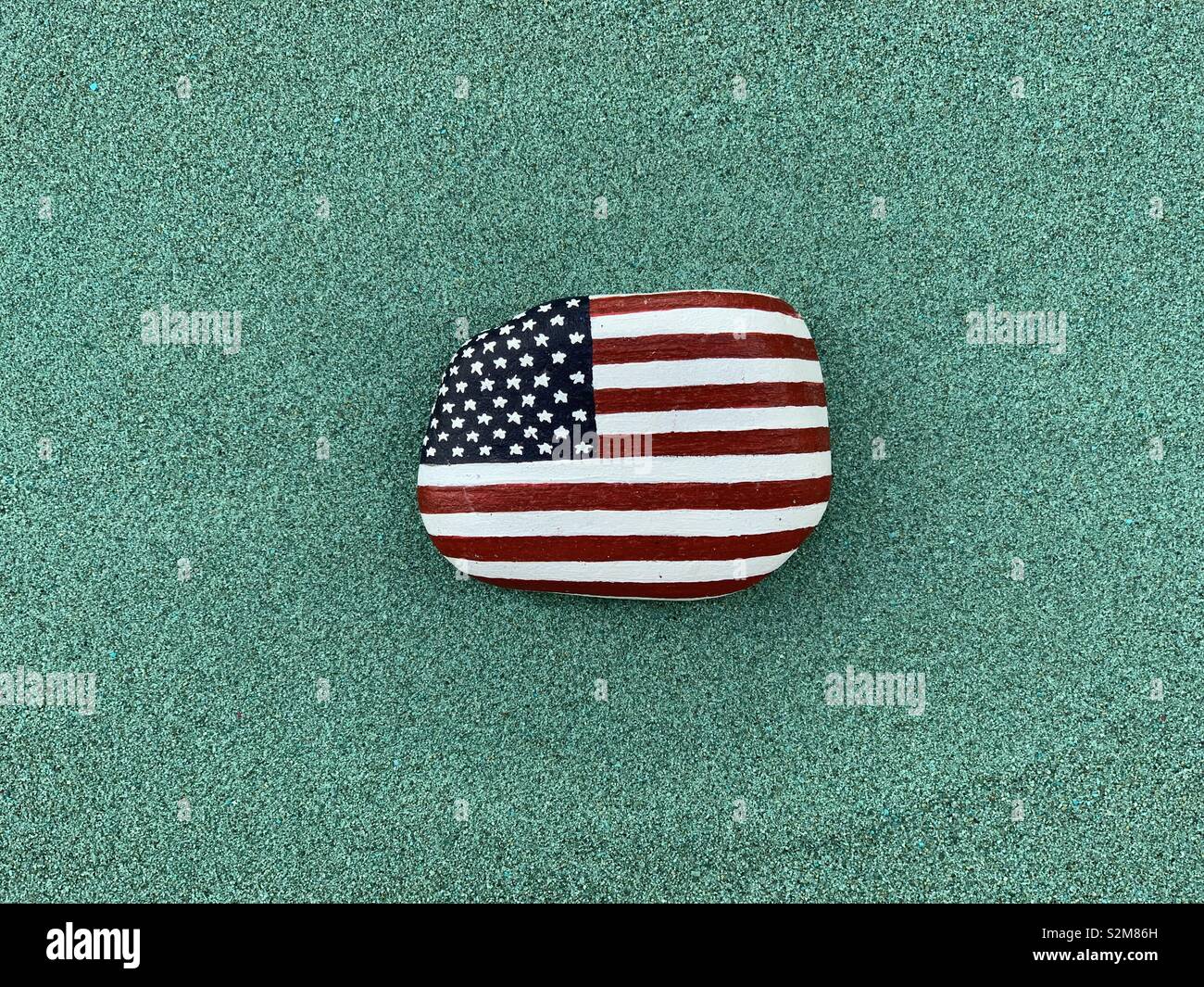 United States of America, national flag painted on a stone over green sand - Smartphone Captured Stock Image