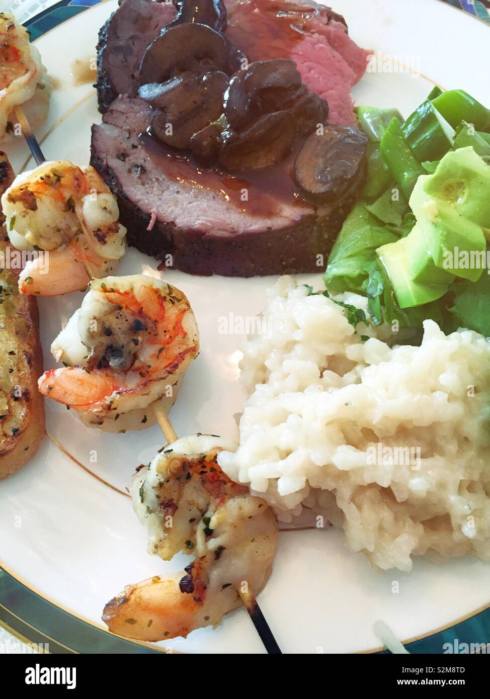 Close up flat lay of a well-balanced meal of beef tenderloin, skewered shrimp and rice with a side of salad, USA - Smartphone Captured Stock Image