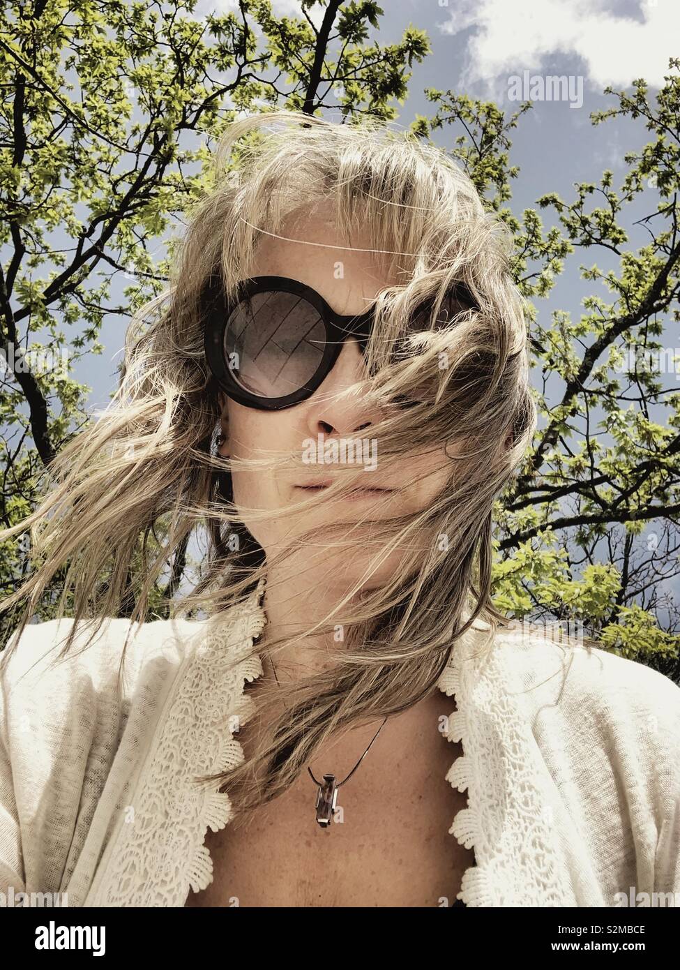 Woman under a tree on a windy day. - Smartphone Captured Stock Image