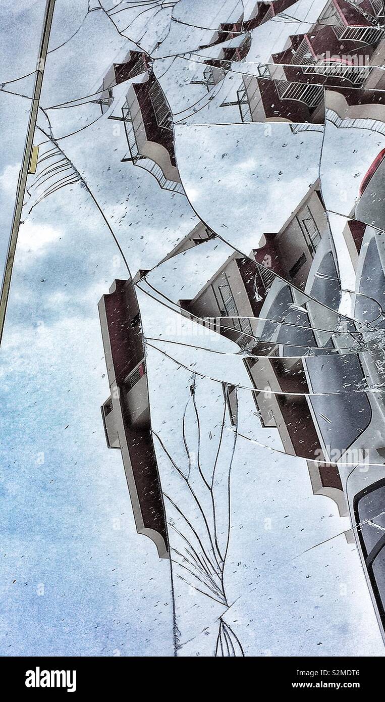 Buildings and sky reflected in a shattered mirror on a street Stock Photo