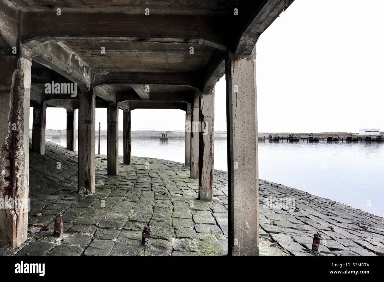 Concrete pillars underneath abandoned harbour structure Stock Photo