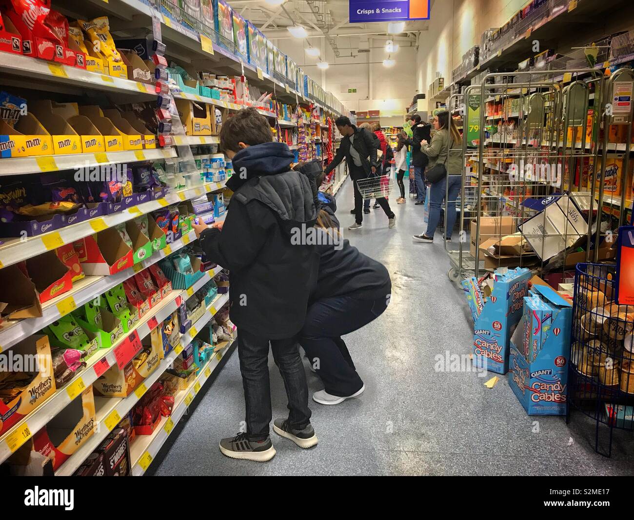 People shopping in a supermarket. Customers browse items on the shelves. - Smartphone Captured Stock Image