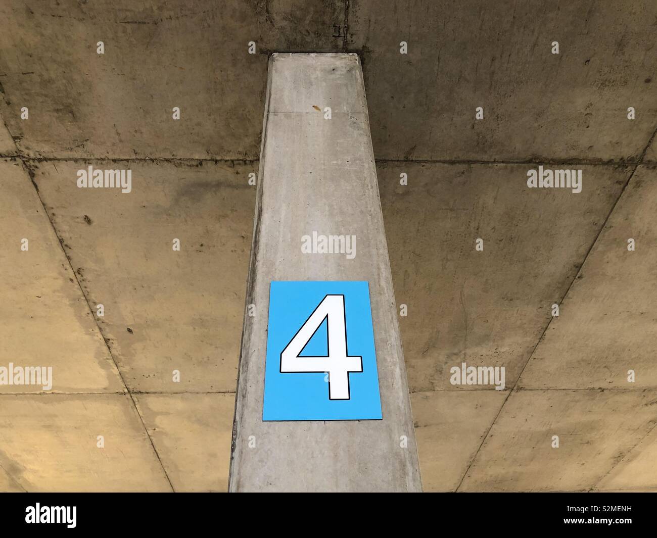 The number four on a concrete pylon in an undercover parking. - Smartphone Captured Stock Image