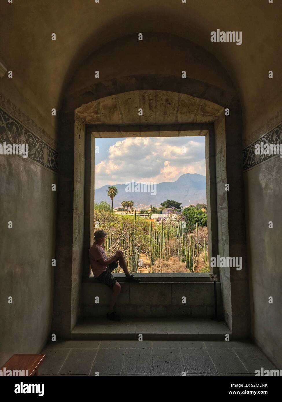 Man resting in window overlooking gardens of Museum of Cultures of Oaxaca, Santo Domingo, Oaxaca City, Oaxaca, Mexico Stock Photo