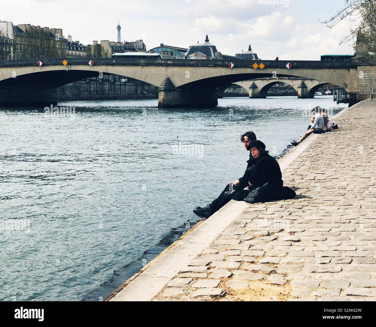 young couples enjoying sun on Seine river bank in Paris Stock Photo