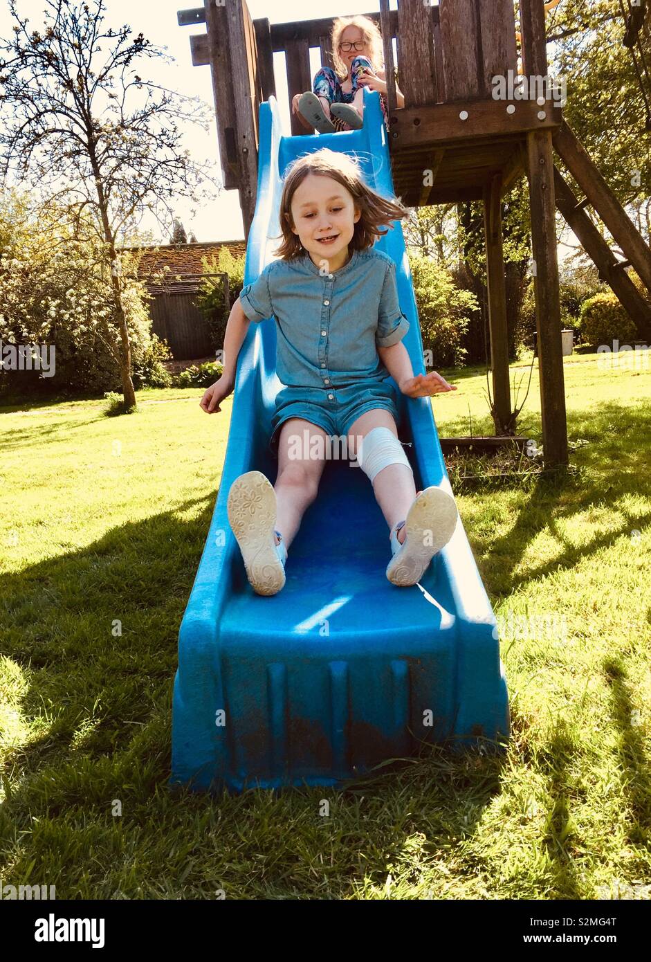 Sisters playing on a slide in garden - Smartphone Captured Stock Image
