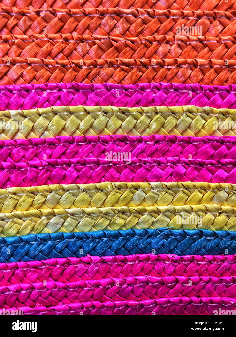 Horizontal straw weave pattern with bright pink, orange, blue, and yellow colors. - Smartphone Captured Stock Image