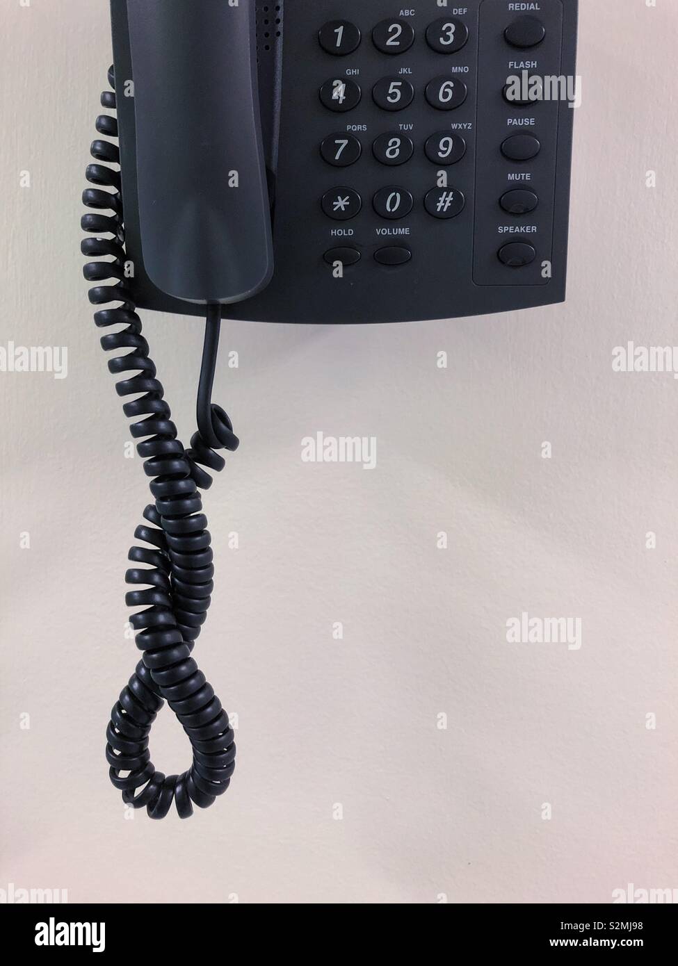 Part of a landline telephone against a white wall. Stock Photo