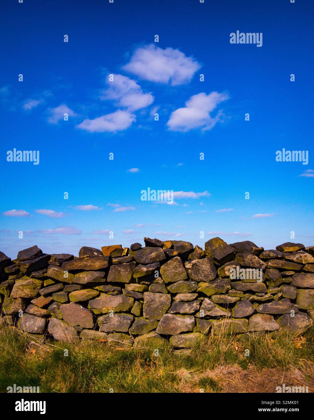 View of drystone wall with blue sky and clouds above. - Smartphone Captured Stock Image