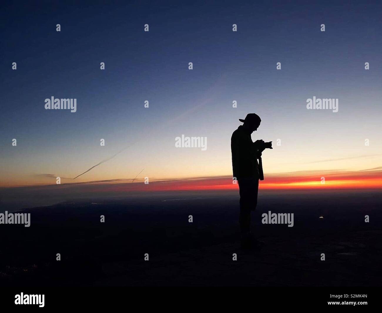 Silhouette of a photographer using his camera at sunrise Stock Photo