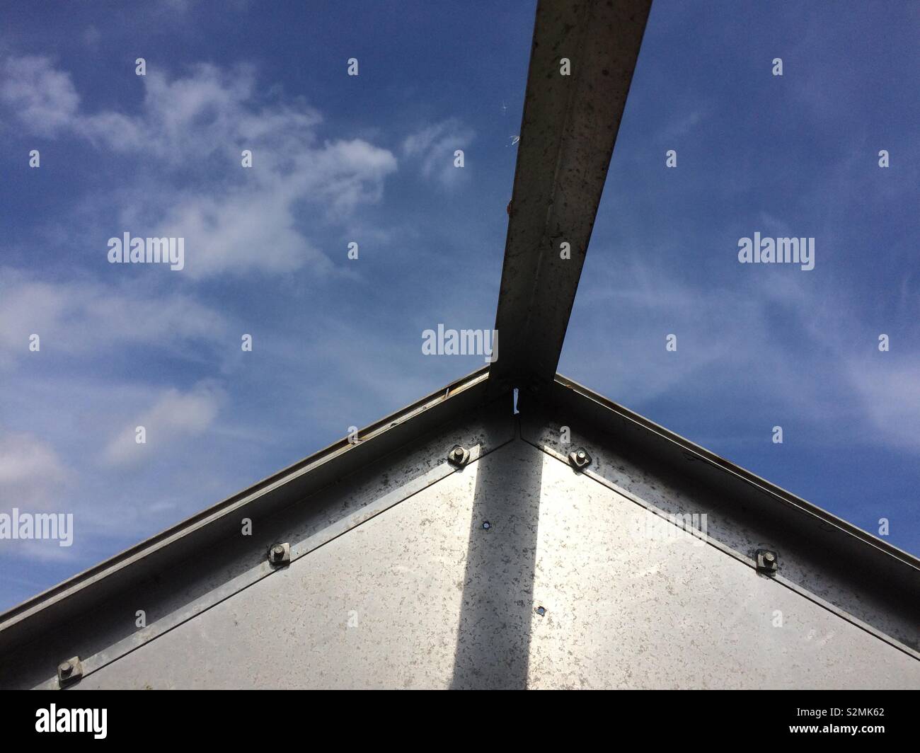 Detail of metallic structure of green house and view of blue sky and clouds - Smartphone Captured Stock Image