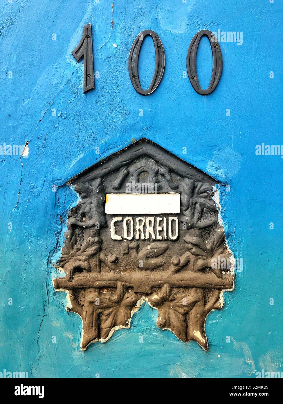 An old mailbox built into a painted blue building exterior. - Smartphone Captured Stock Image