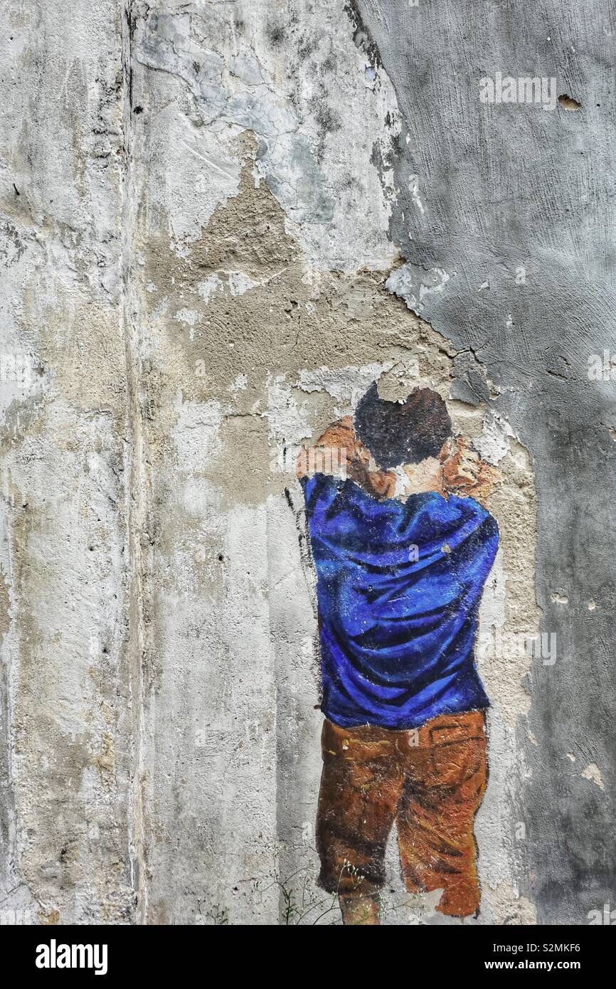 Street art in asia: crying boy with blue shirt. Painted on a gray wall. Sad times ... Stock Photo