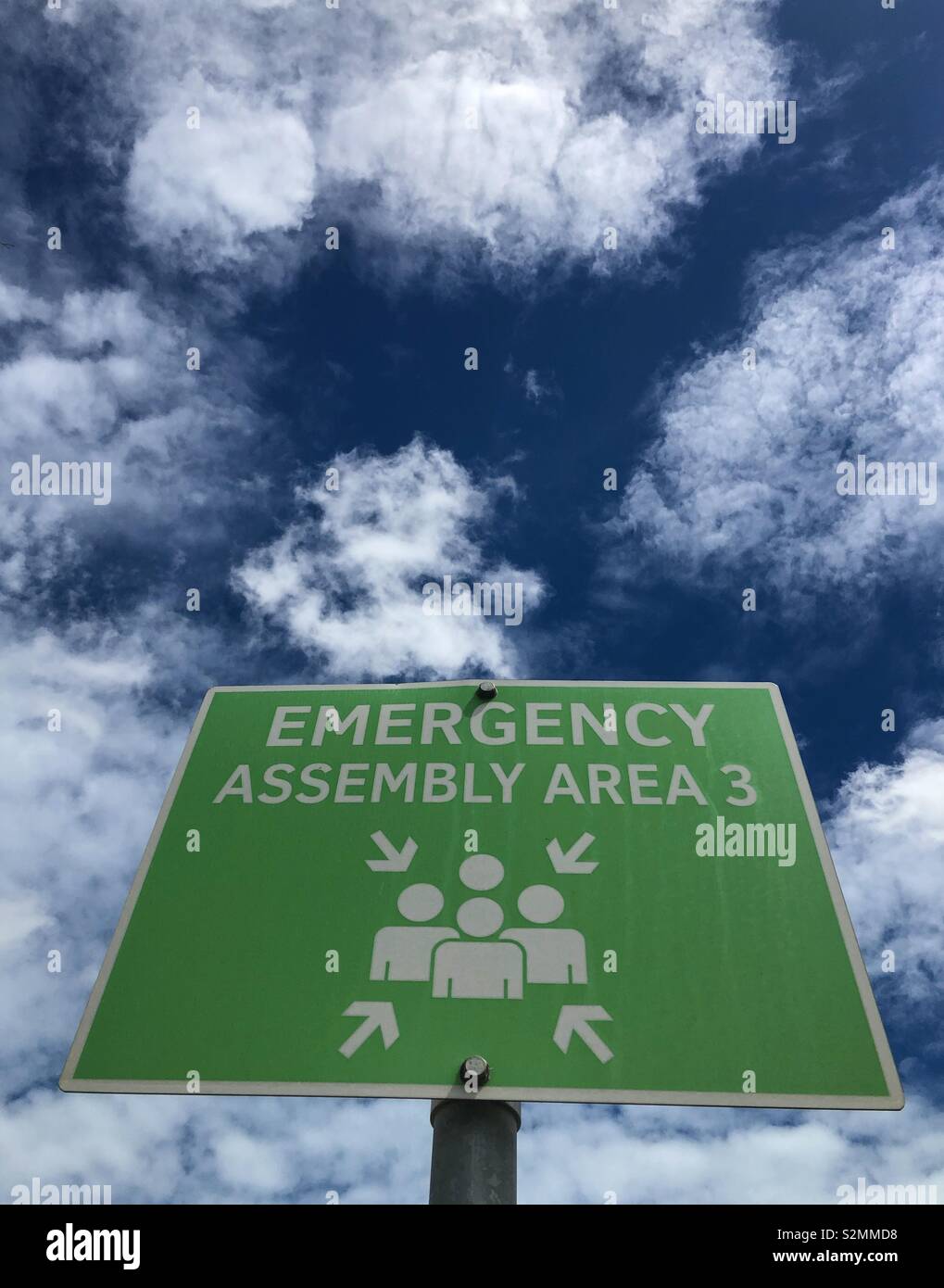 An emergency assembly area sign against a cloudy sky. - Smartphone Captured Stock Image An emergency assembly area sign against a cloudy sky. - Smartphone Captured Stock Image