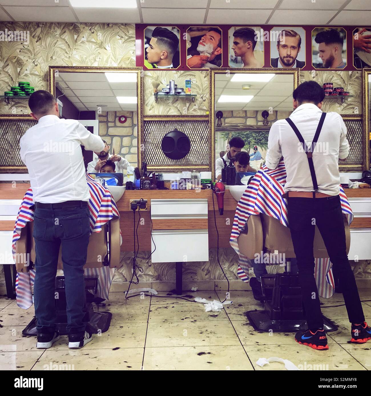 Babrers at work in a barbers shop cutting hair. - Smartphone Captured Stock Image