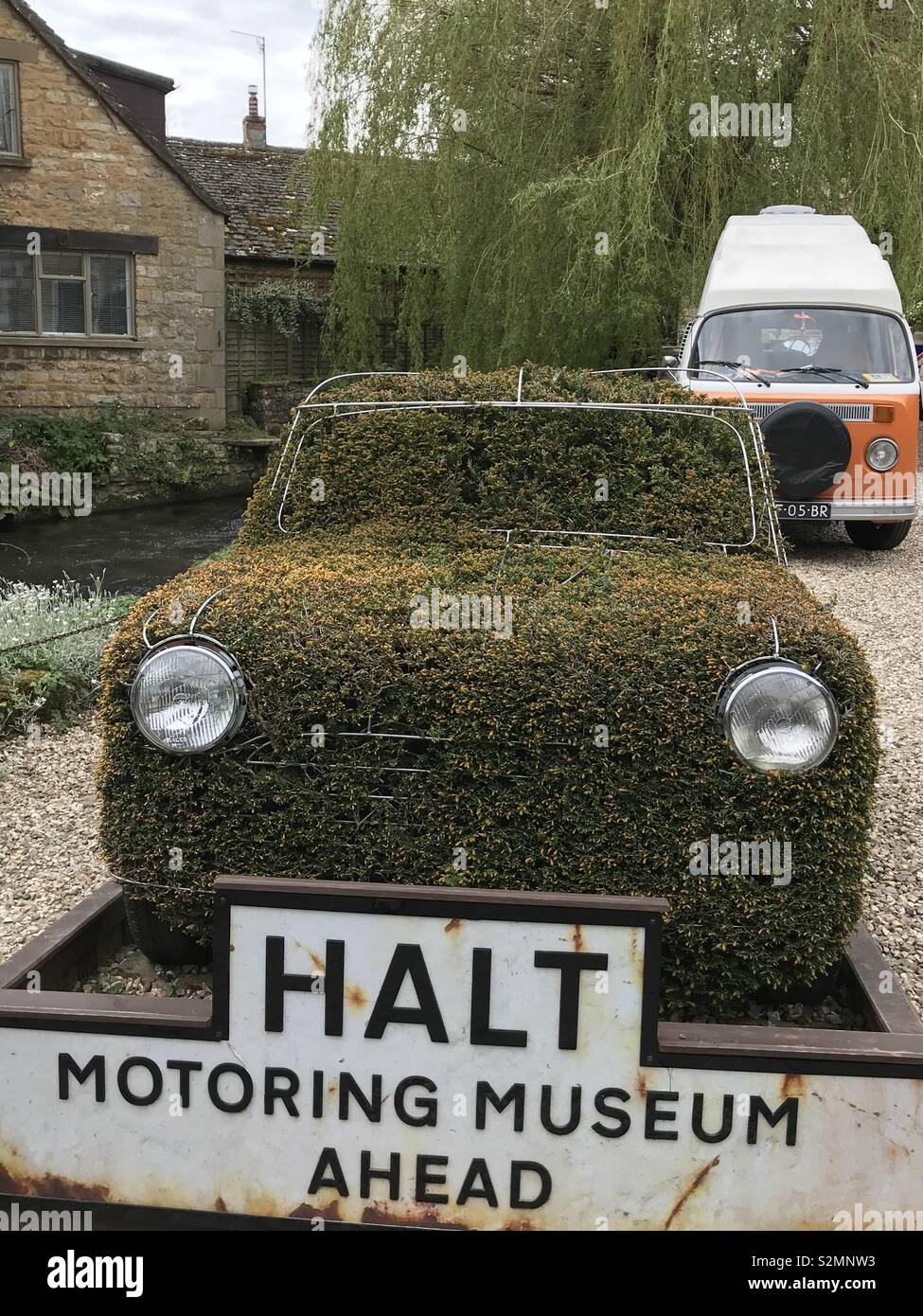 Grass covered car at the entrance to a motor museum Stock Photo