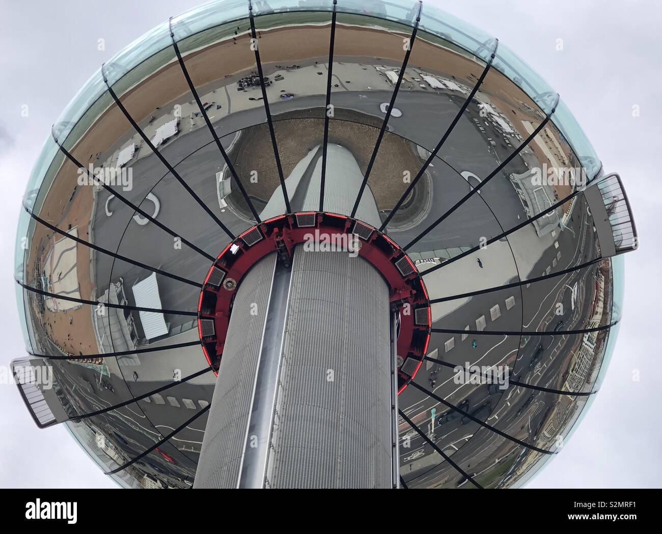 An unusual perspective of The British Airways i360 looking at the reflection of Brighton pleasure beach and seafront in the base of the gondola. Stock Photo