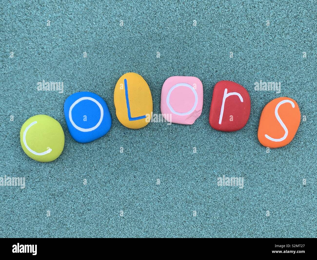 Colors word composed with colored sea stones over green sand - Smartphone Captured Stock Image