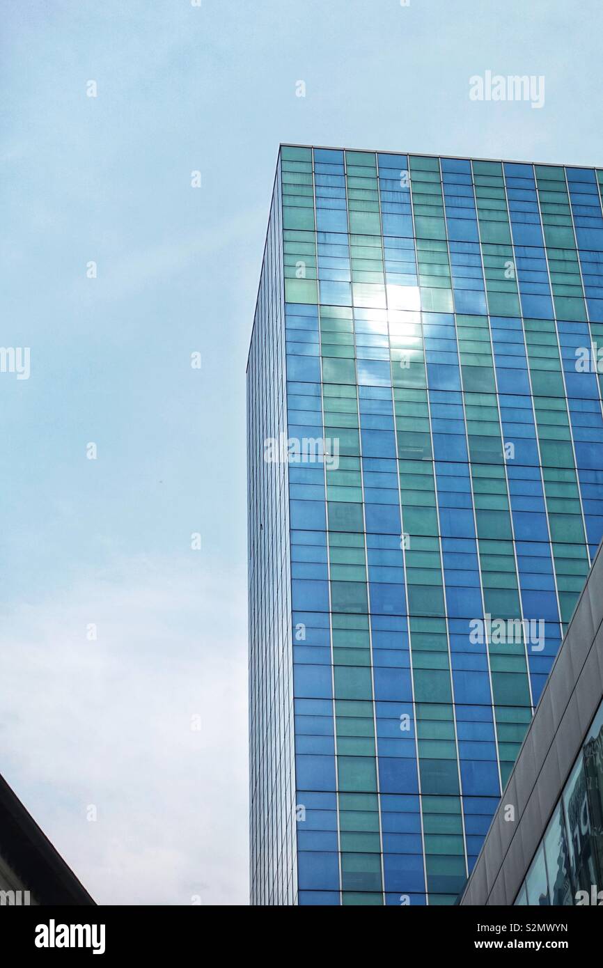 Midday sun reflections in the blue glas facade of a tall office building in singapore, asia. Stock Photo